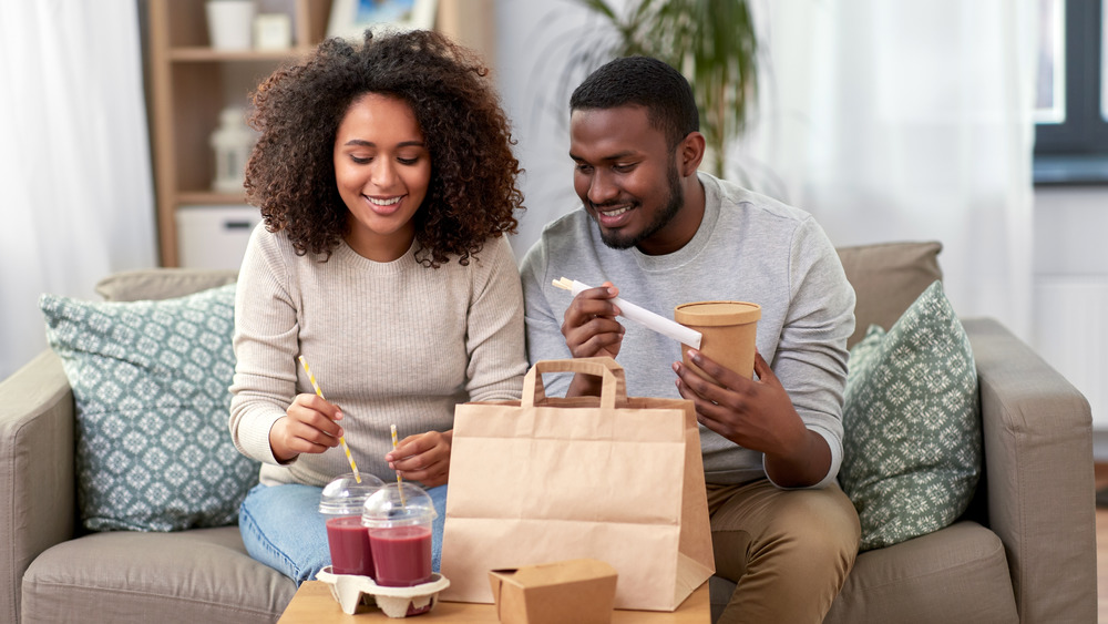 man and woman eating takeout at home