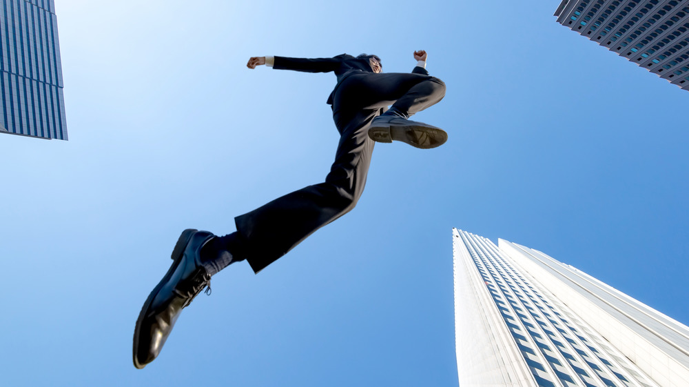 bottom view of a tall business man jumping in air
