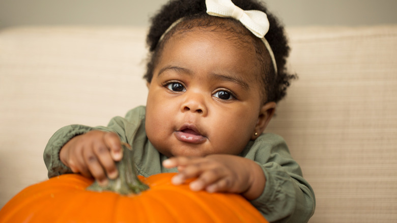 autumn baby holding pumpkin