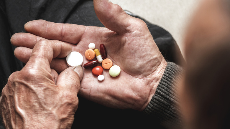 hands of mature man holding many pills