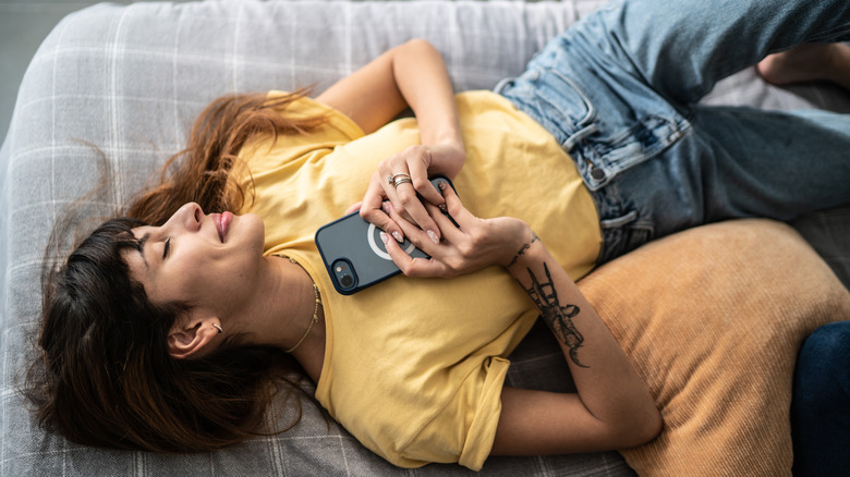 Woman in love holding phone in bed