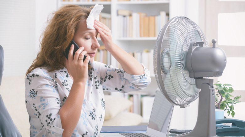 woman using a fan to cool her hot flash