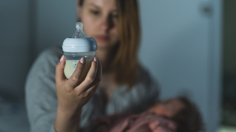 mother looking at baby bottle