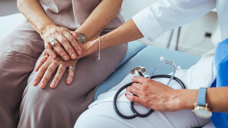 doctor's hand covering patient's hands