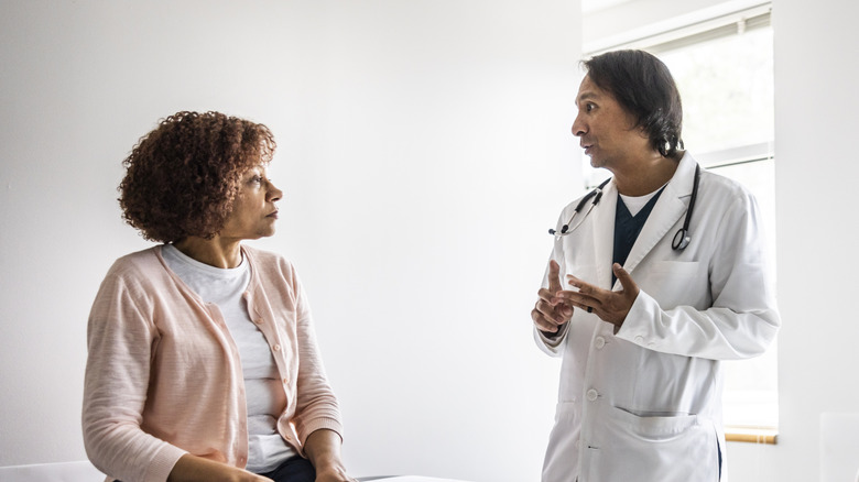 A doctor talking to a female patient in an exam room