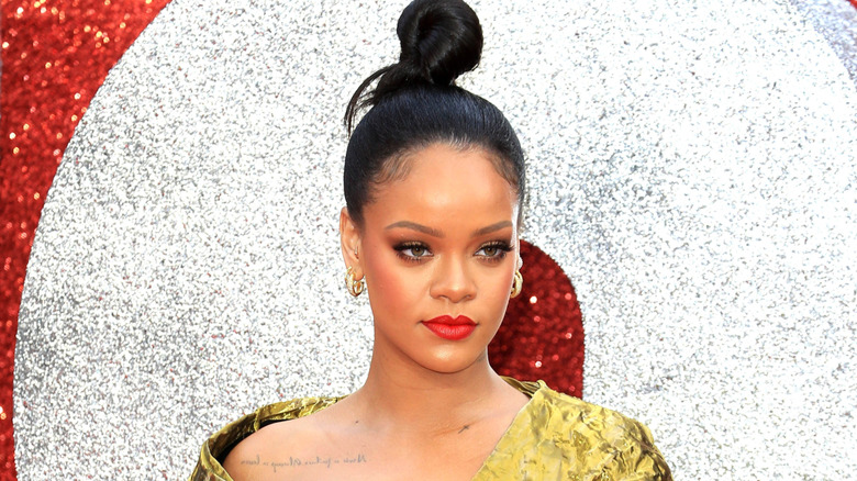 Rihanna with hair up on her head in golden gown