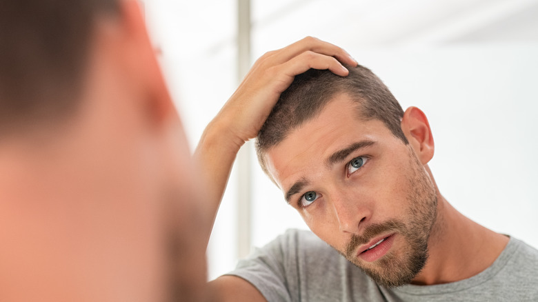 A man looking critically at himself in a mirror