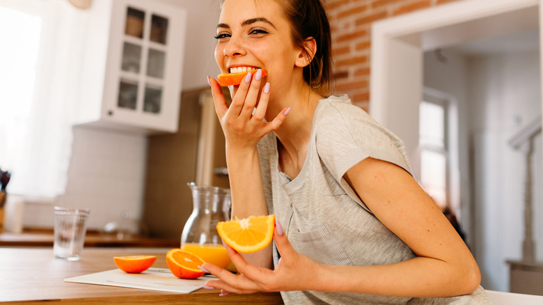 smiling woman eating orange slices