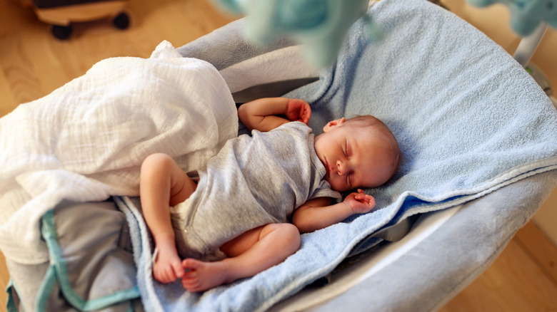Newborn baby sleeps in inclined bouncer