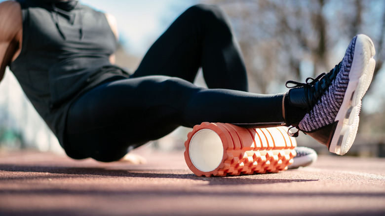 Man using foam roller on leg