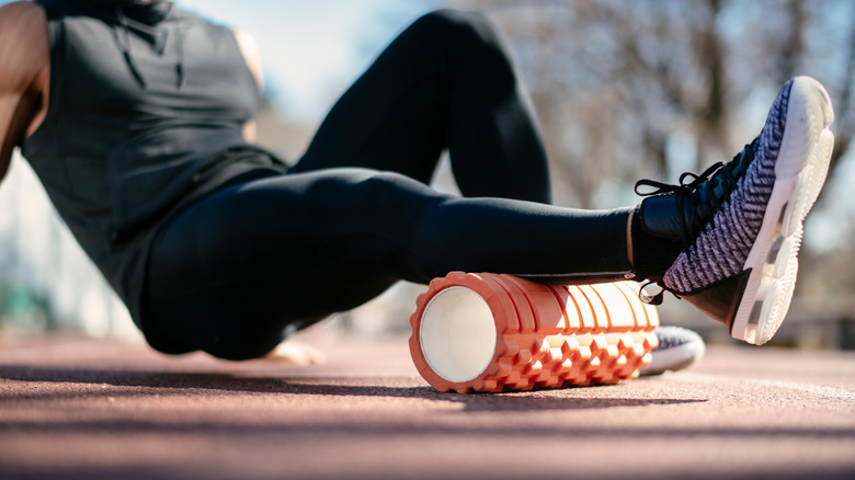 Man using foam roller on leg