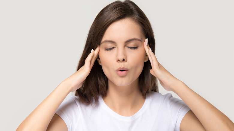 Woman holding temples and exhaling