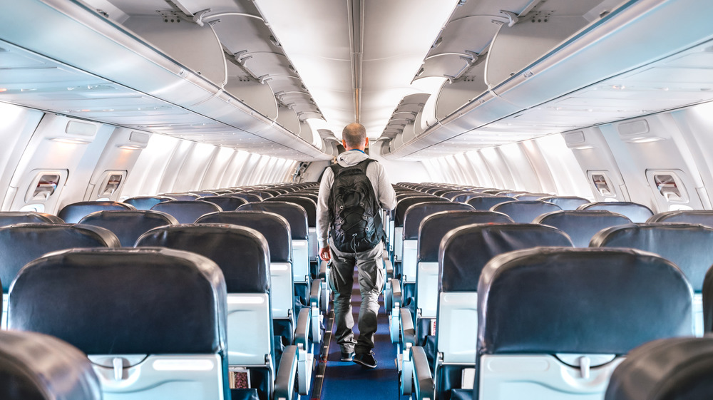 Stock photo of a lone male traveler in the aisle of an airplane