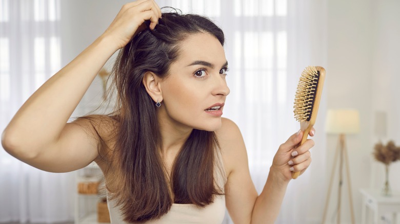 woman looking at her scalp and hair in the mirror