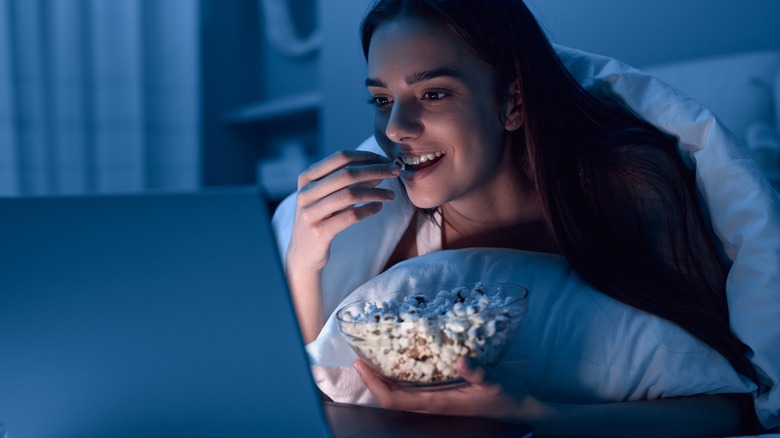 a woman eating food in bed 