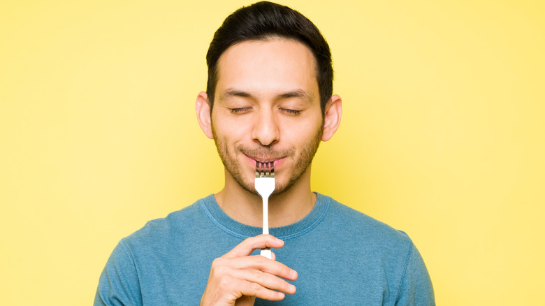 man with fork in mouth