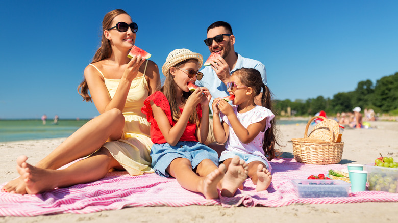 A family eating watermelon slices at the beach