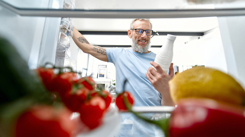 Smiling older man looking at fridge contents