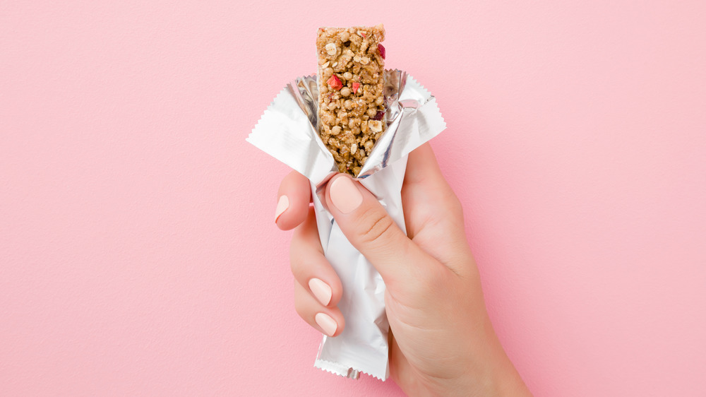 woman's hand holding opened granola bar