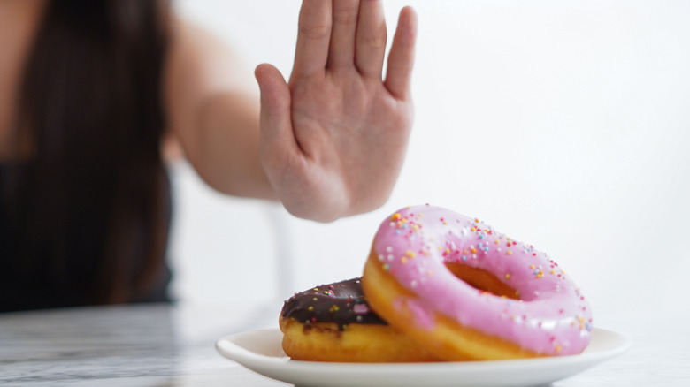Woman rejecting two donuts on a plate