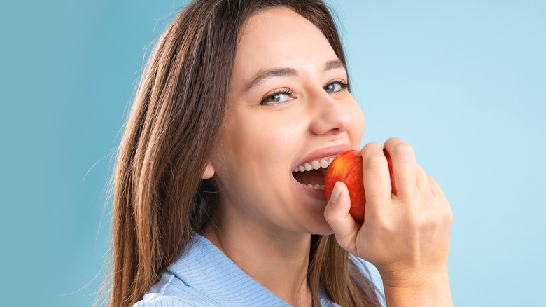 woman smiling eating red apple