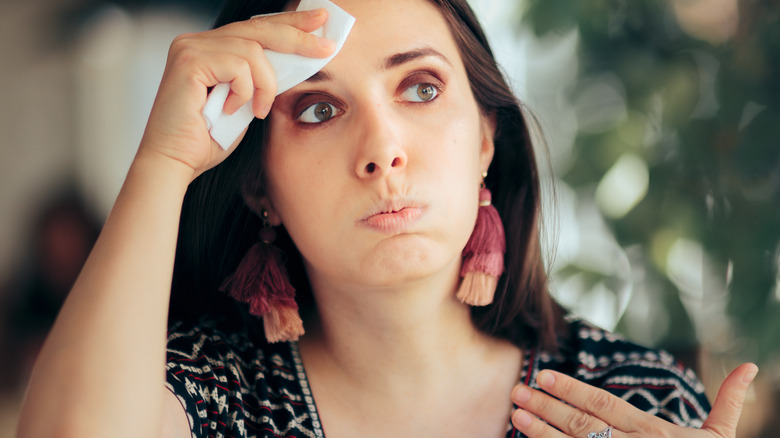 Woman feeling warm and blotting forehead