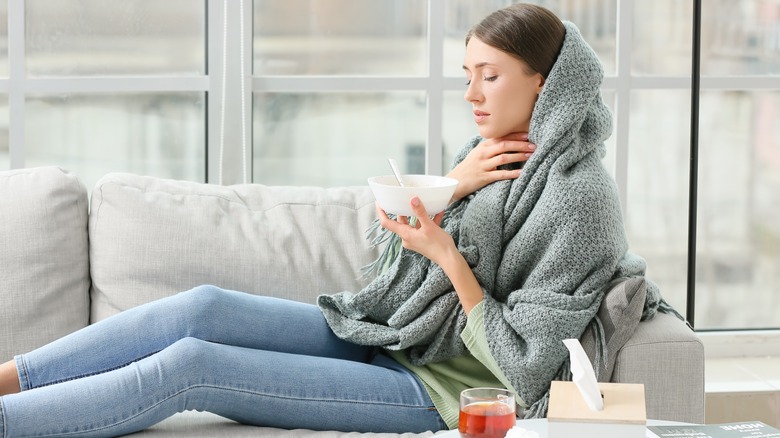 Sick woman on couch wrapped in blanket