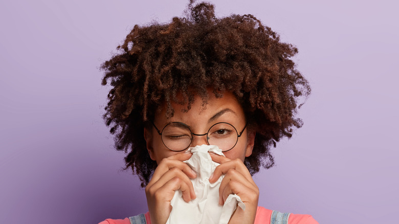 woman sneezing into tissue