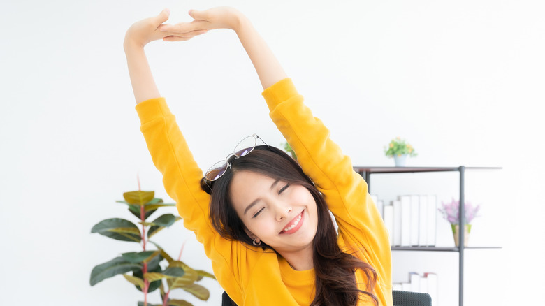 a young woman stretching while on her laptop