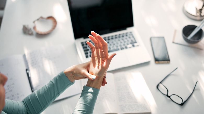 a woman massaging her wrist and hand at work 