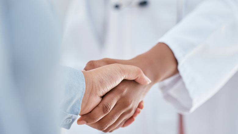 patient and doctor shaking hands in partnership