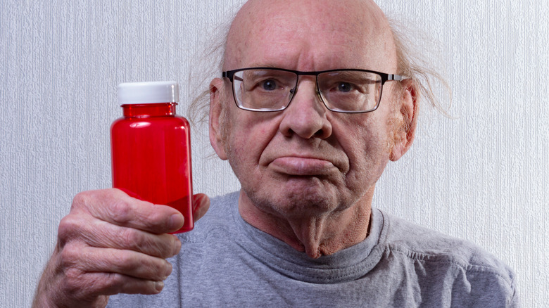 old man holding empty pill bottle 