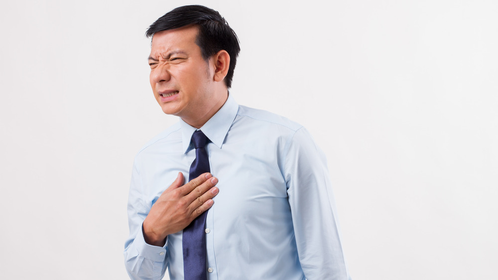 A distressed man rubbing his chest due to heartburn