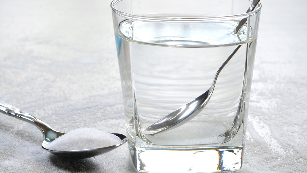Salt water in a glass cup and salt in a teaspoon