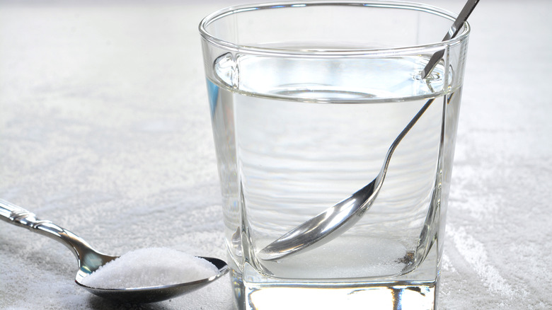 Salt water in a glass cup and salt in a teaspoon