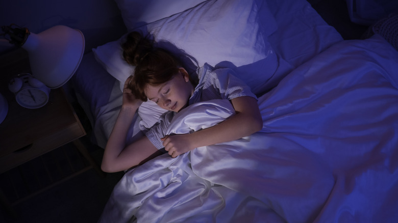 A teenager wearing shoes in bed