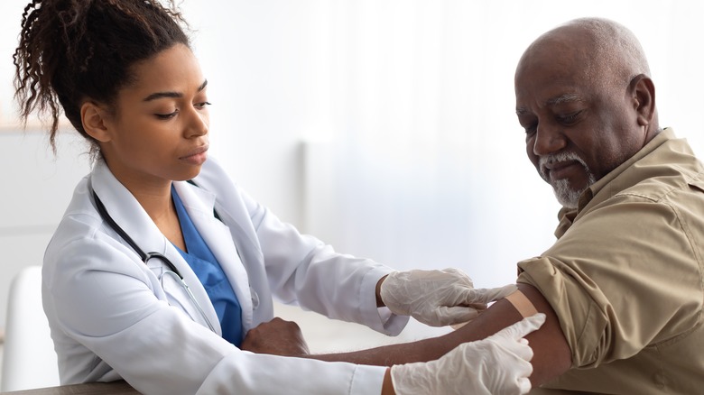 doctor applying bandaid to patient's injection site