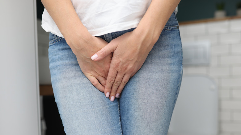 standing woman touching lower abdomen