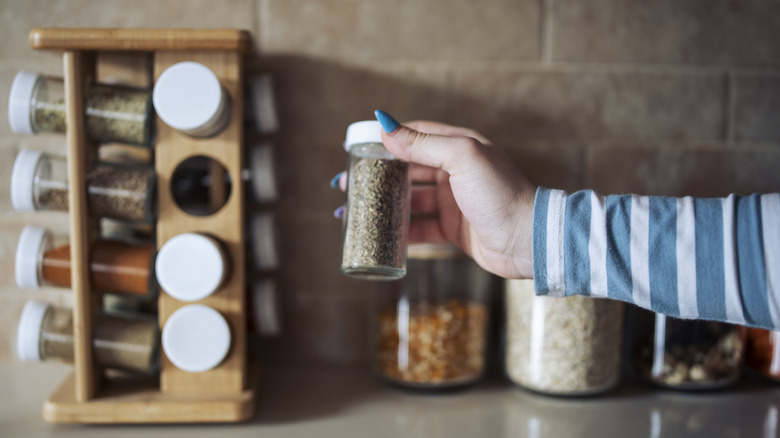 Hand grabbing jar from spice rack