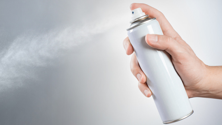 Hand spraying can of aerosol hair spray