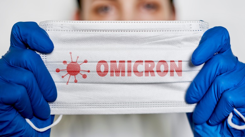 A healthcare worker holds a mask that reads omicron