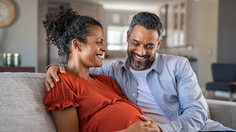 Man and pregnant woman smiling and holding her stomach