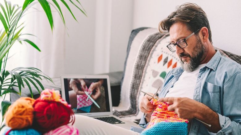 A man sitting on his couch and knitting