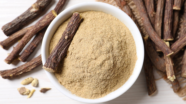 dried licorice root beside bowl of ground licorice root