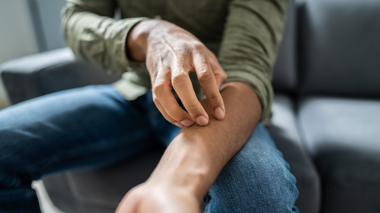 Man scratching inside of arm