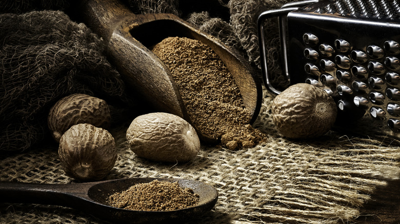 nutmeg seeds and powdered nutmeg on a rustic table