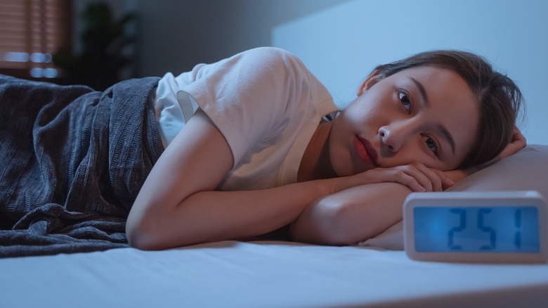 Woman awake in bed by a clock