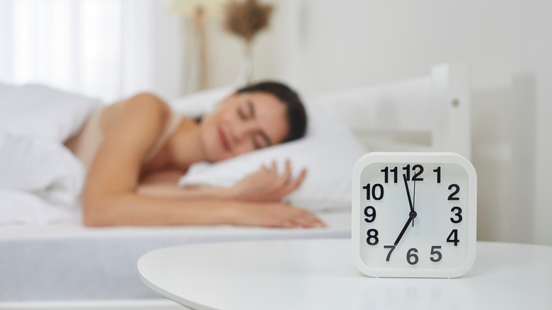 Woman sleeping in bed with clock