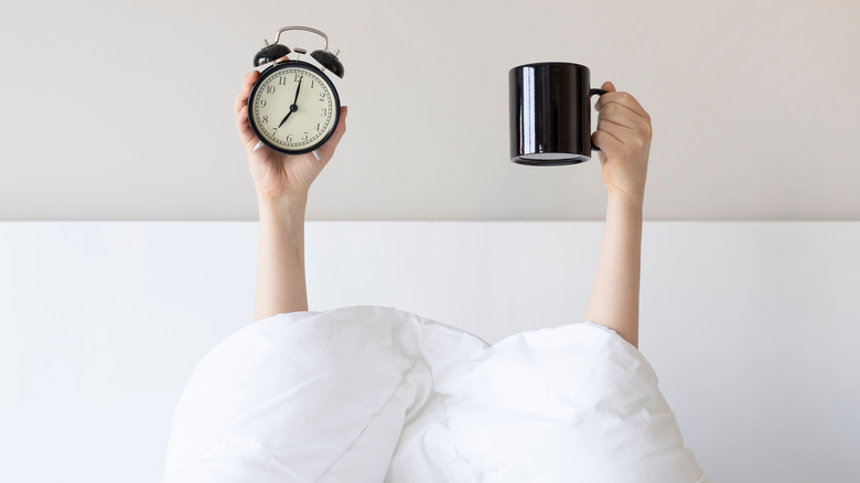 Hands holding clock and mug