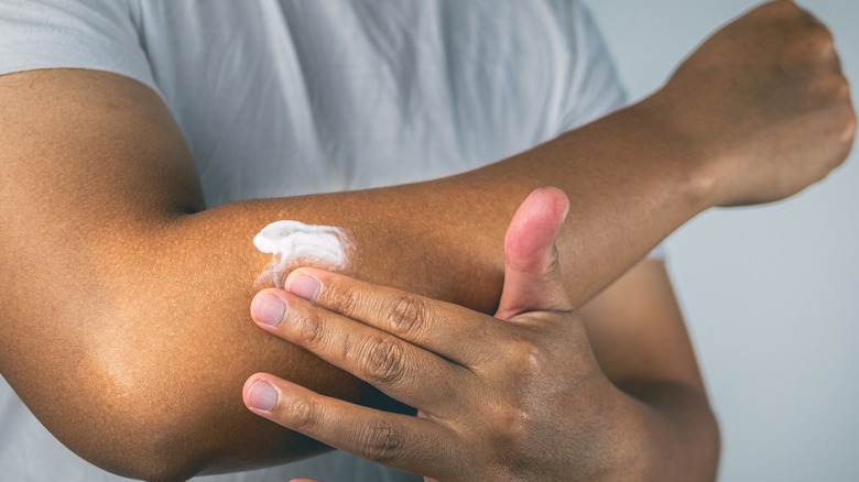 Hand rubbing cream into arm